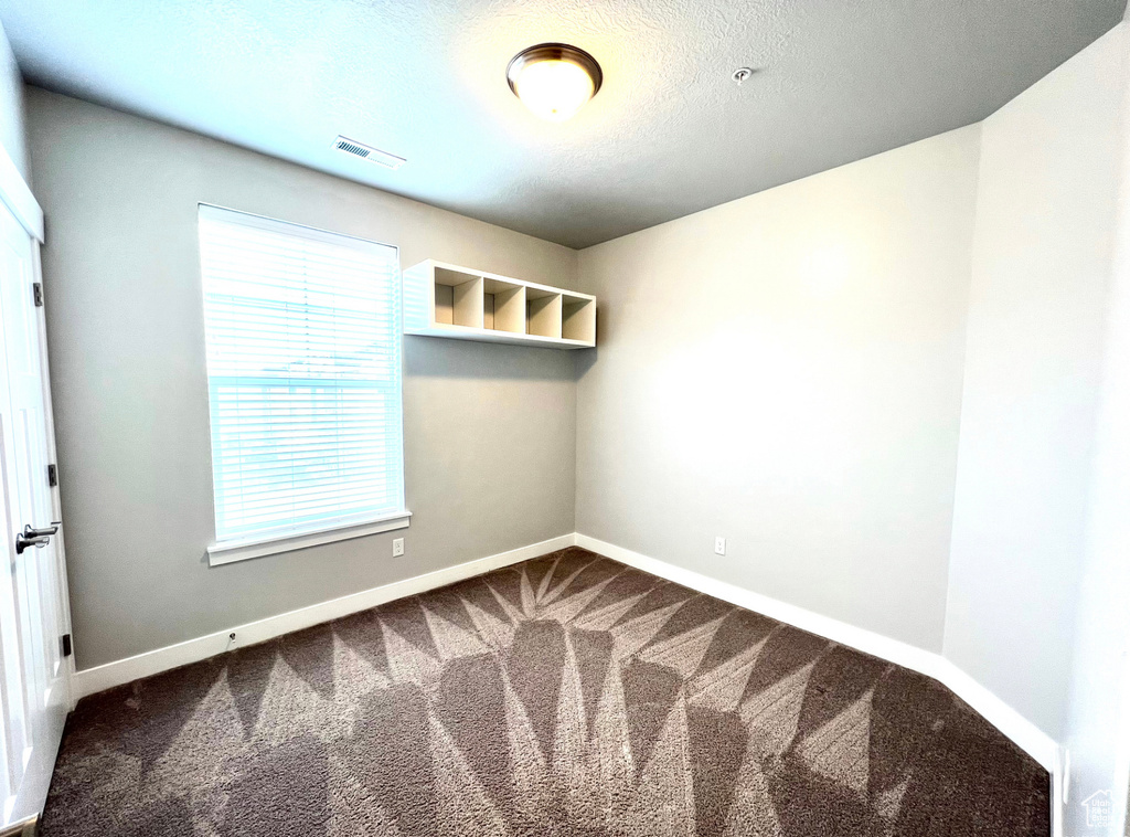 Empty room featuring a wealth of natural light and dark carpet