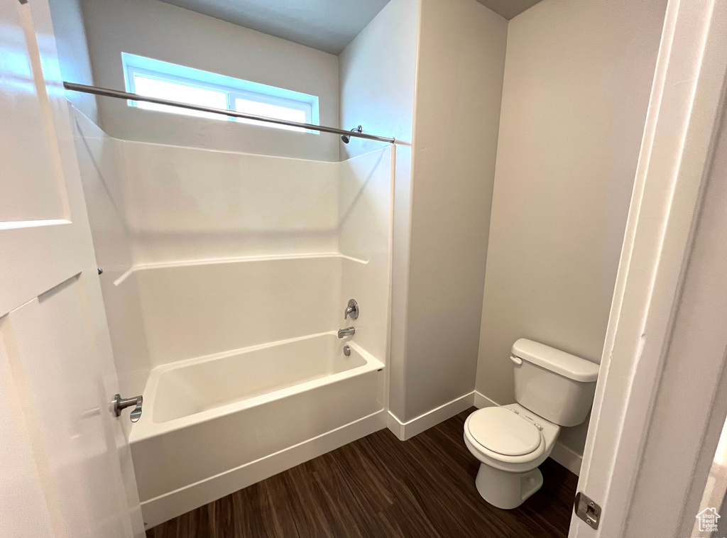 Bathroom with tub / shower combination, wood-type flooring, and toilet