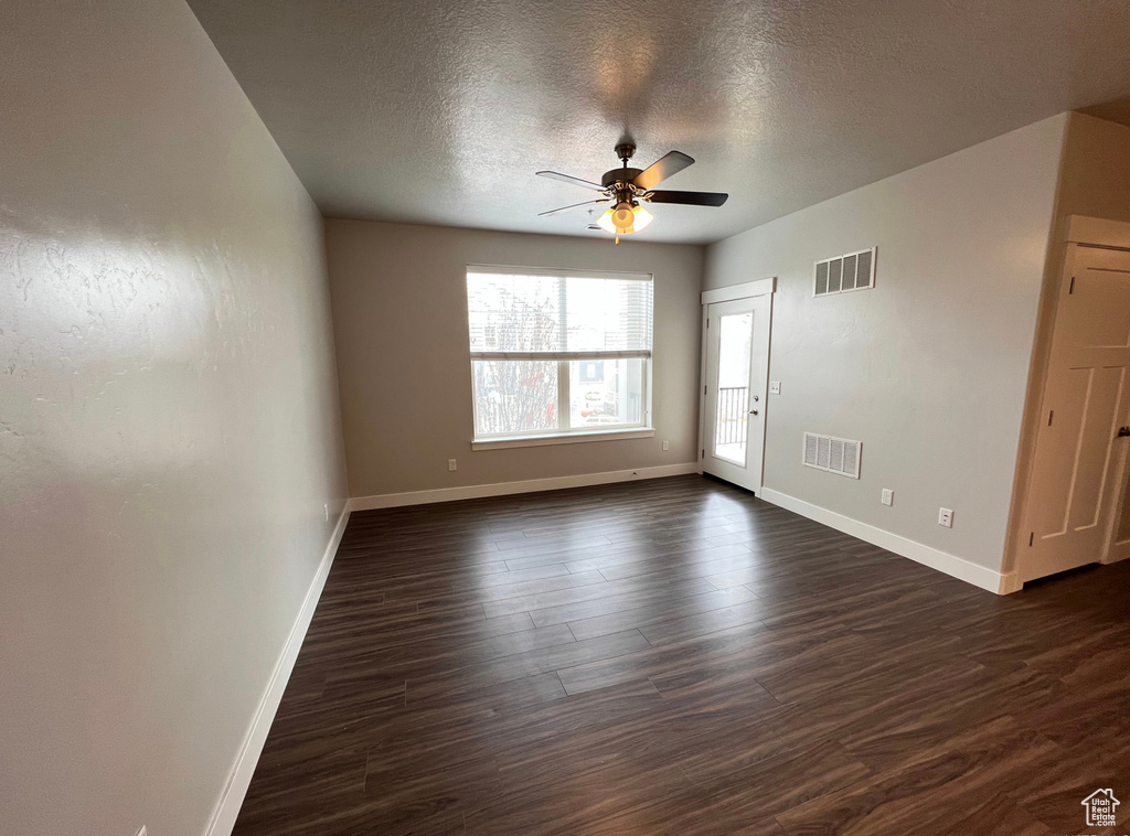 Unfurnished room with dark hardwood / wood-style flooring, ceiling fan, and a textured ceiling