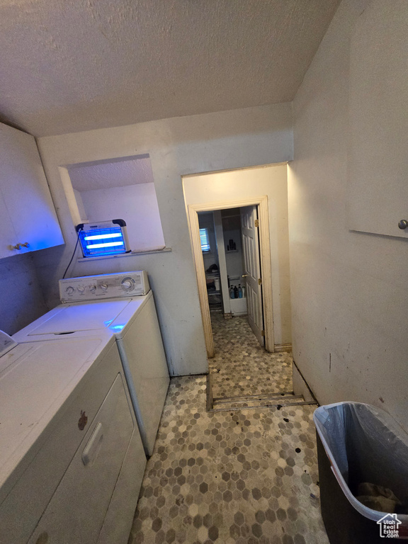 Clothes washing area featuring independent washer and dryer, light tile flooring, and a textured ceiling