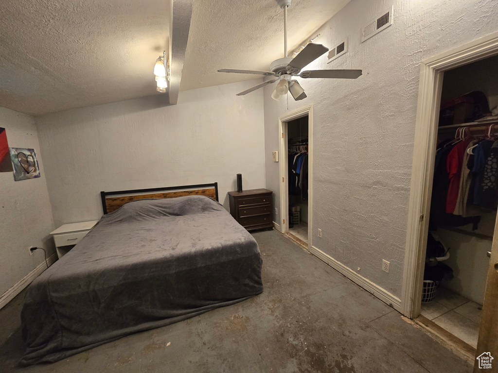 Bedroom featuring a walk in closet, ceiling fan, concrete floors, and a closet