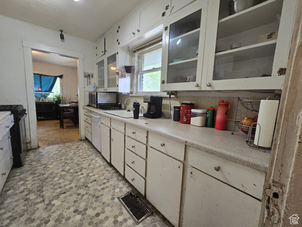Kitchen with white cabinets, sink, stainless steel appliances, and light tile floors