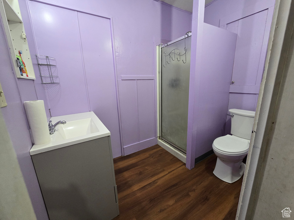 Bathroom with a shower with shower door, wood-type flooring, vanity, and toilet