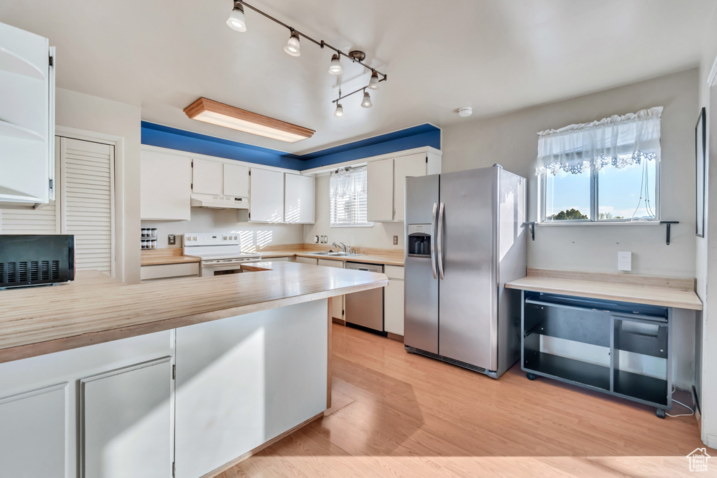 Kitchen featuring appliances with stainless steel finishes, light hardwood / wood-style flooring, track lighting, white cabinets, and sink