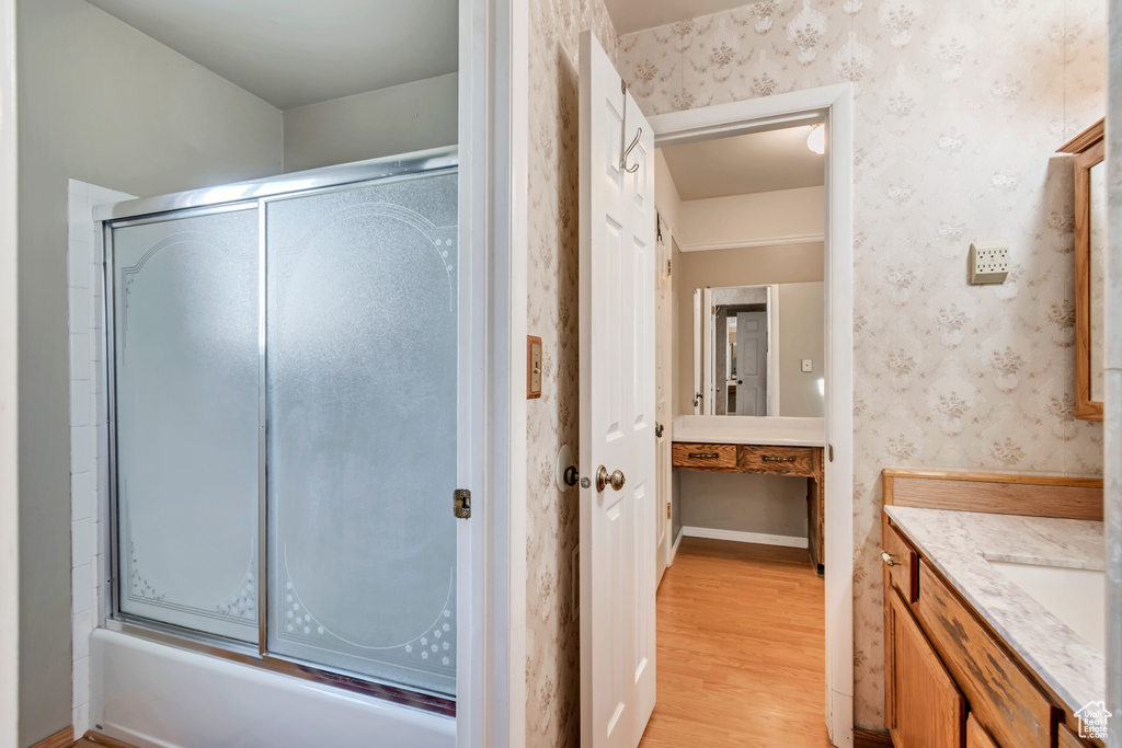Bathroom featuring bath / shower combo with glass door, vanity, and hardwood / wood-style floors