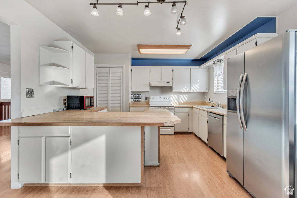 Kitchen with rail lighting, appliances with stainless steel finishes, and light wood-type flooring