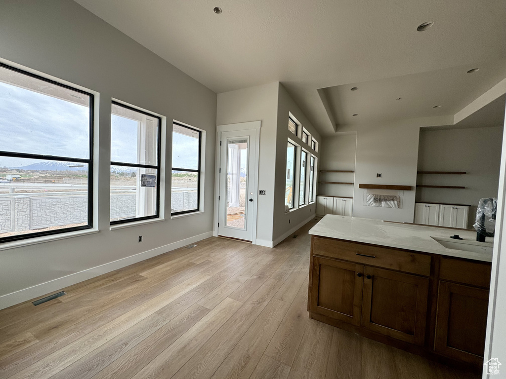 Kitchen featuring light hardwood / wood-style floors, sink, and light stone countertops