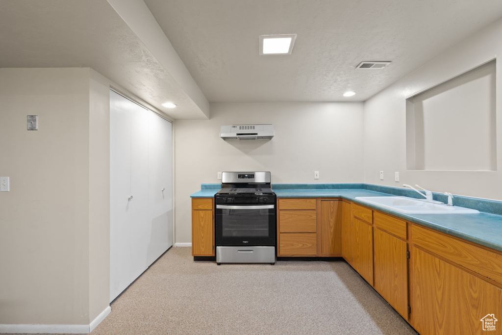 Kitchen with light colored carpet, electric stove, a textured ceiling, and sink