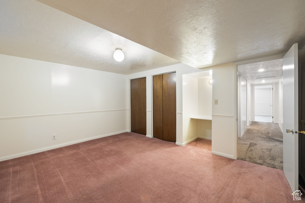 Unfurnished bedroom with carpet flooring, a textured ceiling, and multiple closets