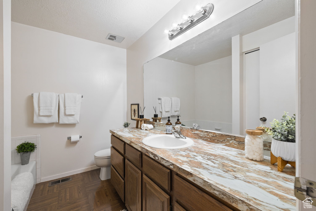Bathroom featuring vanity, parquet floors, and toilet