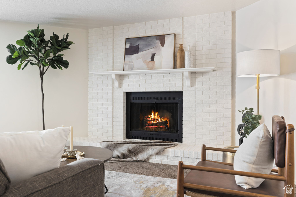 Living area with carpet flooring, a brick fireplace, and a textured ceiling