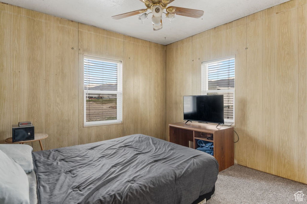 Bedroom featuring wooden walls, carpet, and ceiling fan