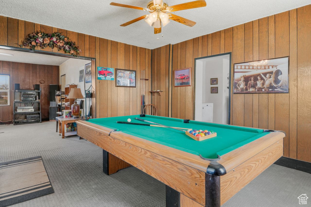 Playroom featuring ceiling fan, a textured ceiling, pool table, wooden walls, and dark colored carpet