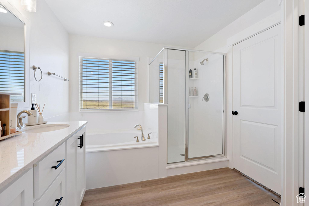 Bathroom featuring shower with separate bathtub, vanity with extensive cabinet space, and hardwood / wood-style flooring