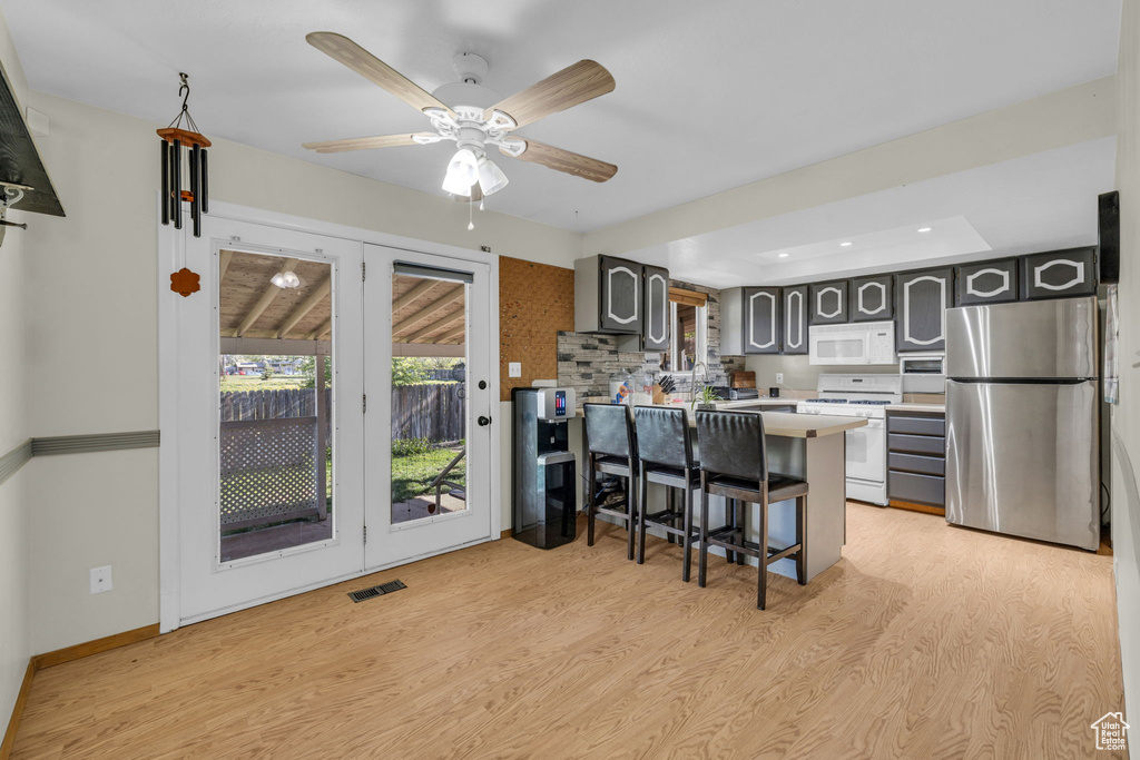 Kitchen with light hardwood / wood-style floors, white appliances, backsplash, and gray cabinets