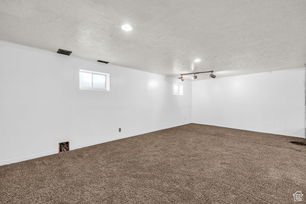 Interior space with track lighting, carpet, and a textured ceiling