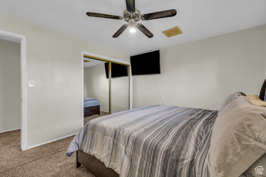 Bedroom with a closet, ceiling fan, and carpet floors