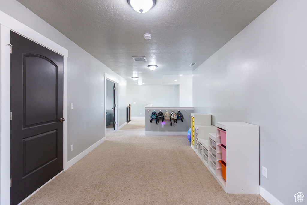 Game room with light colored carpet and a textured ceiling