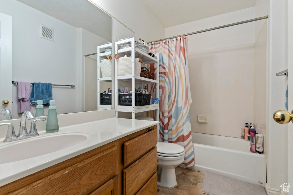 Full bathroom featuring shower / tub combo, vanity, toilet, and tile floors