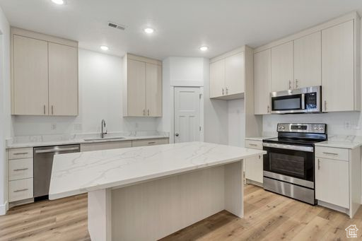 Kitchen with a center island, light hardwood / wood-style flooring, stainless steel appliances, and sink