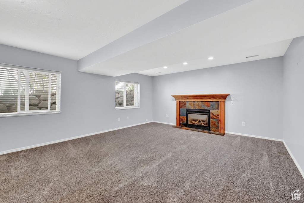 Unfurnished living room with carpet flooring and a tiled fireplace