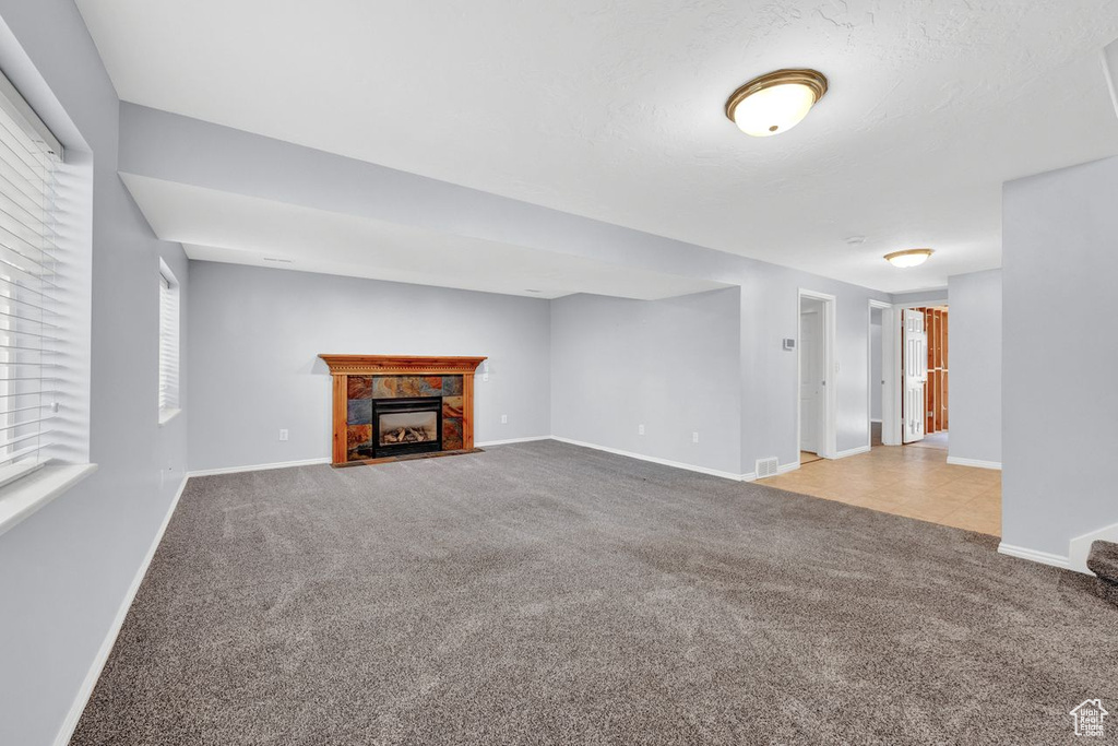 Unfurnished living room with light carpet and a healthy amount of sunlight