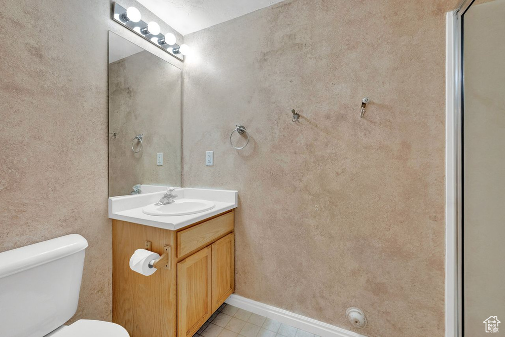 Bathroom with toilet, tile flooring, and large vanity