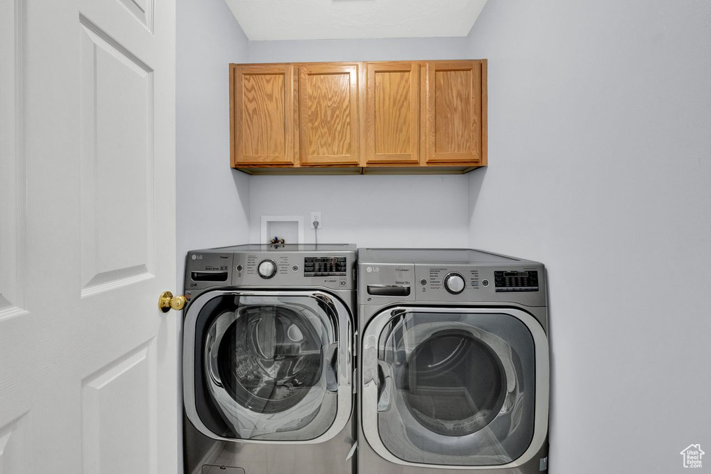 Clothes washing area featuring cabinets, washer hookup, and washing machine and clothes dryer