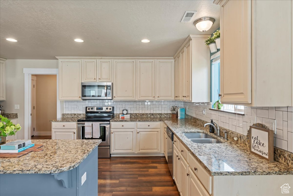 Kitchen featuring appliances with stainless steel finishes, dark hardwood / wood-style flooring, sink, and light stone countertops
