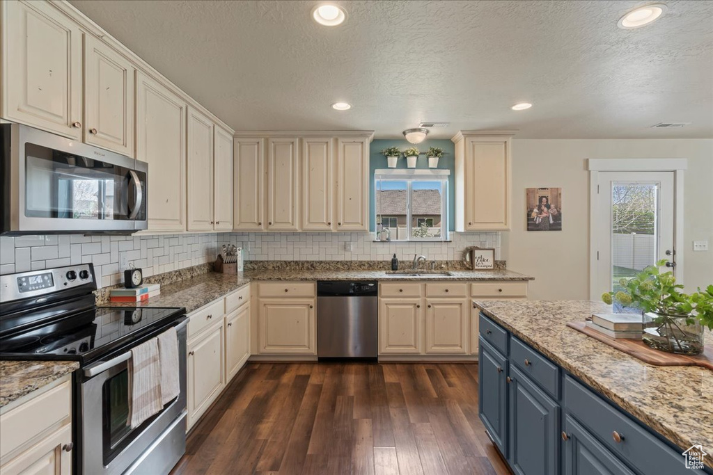 Kitchen featuring backsplash, dark hardwood / wood-style floors, sink, and stainless steel appliances
