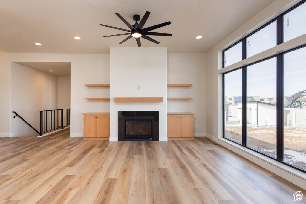 Unfurnished living room featuring light hardwood / wood-style flooring, a wealth of natural light, and ceiling fan