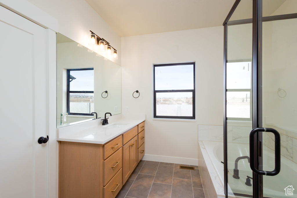 Bathroom with vanity, tiled tub, and tile flooring