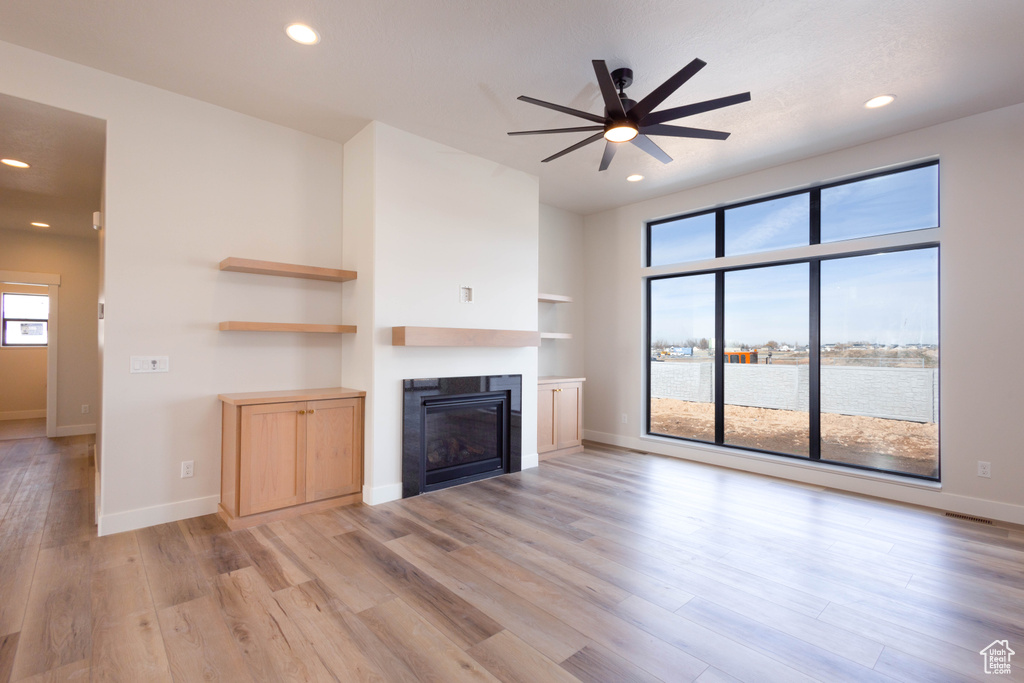 Unfurnished living room featuring ceiling fan, hardwood / wood-style floors, and a water view
