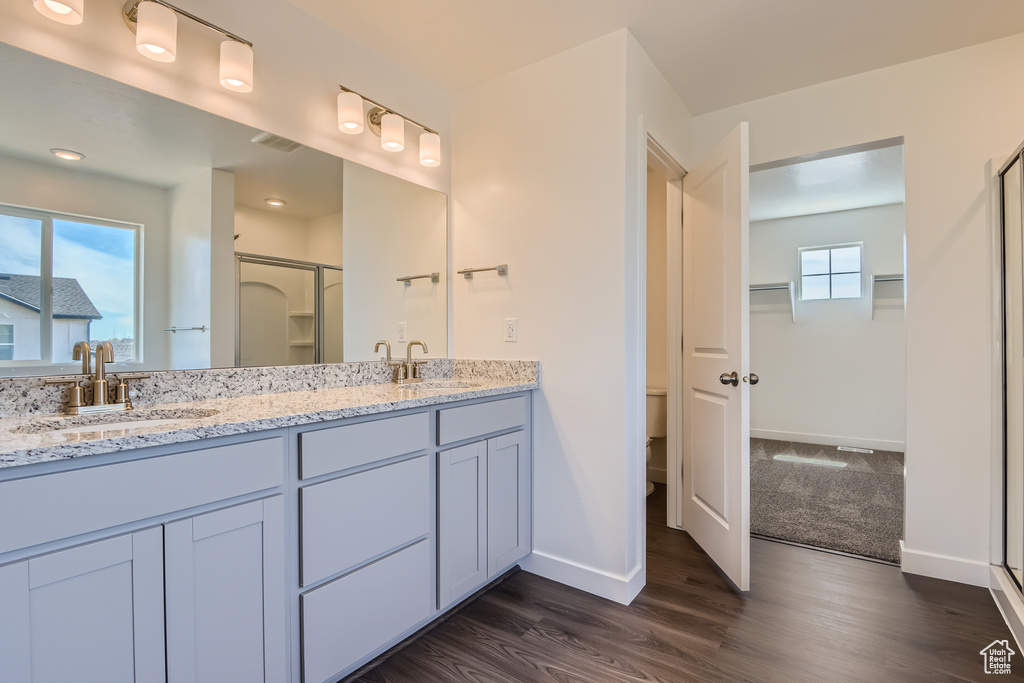 Bathroom featuring walk in shower, wood-type flooring, toilet, and dual vanity