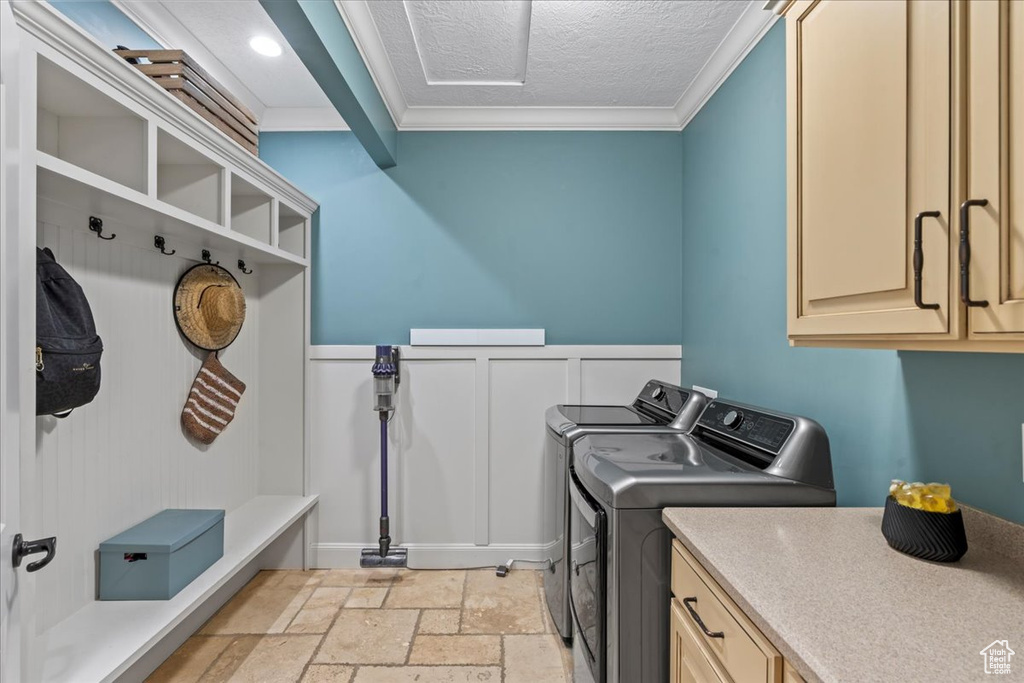Washroom featuring cabinets, light tile floors, a textured ceiling, independent washer and dryer, and ornamental molding