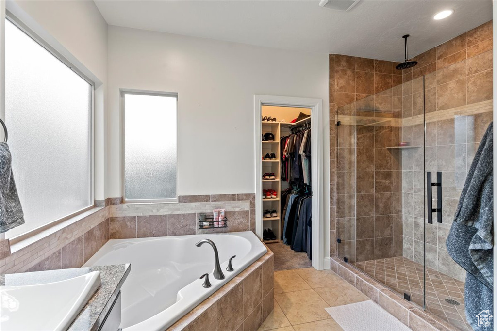 Bathroom featuring a wealth of natural light, tile floors, and separate shower and tub
