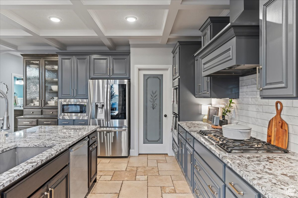 Kitchen with appliances with stainless steel finishes, tasteful backsplash, coffered ceiling, and light tile floors