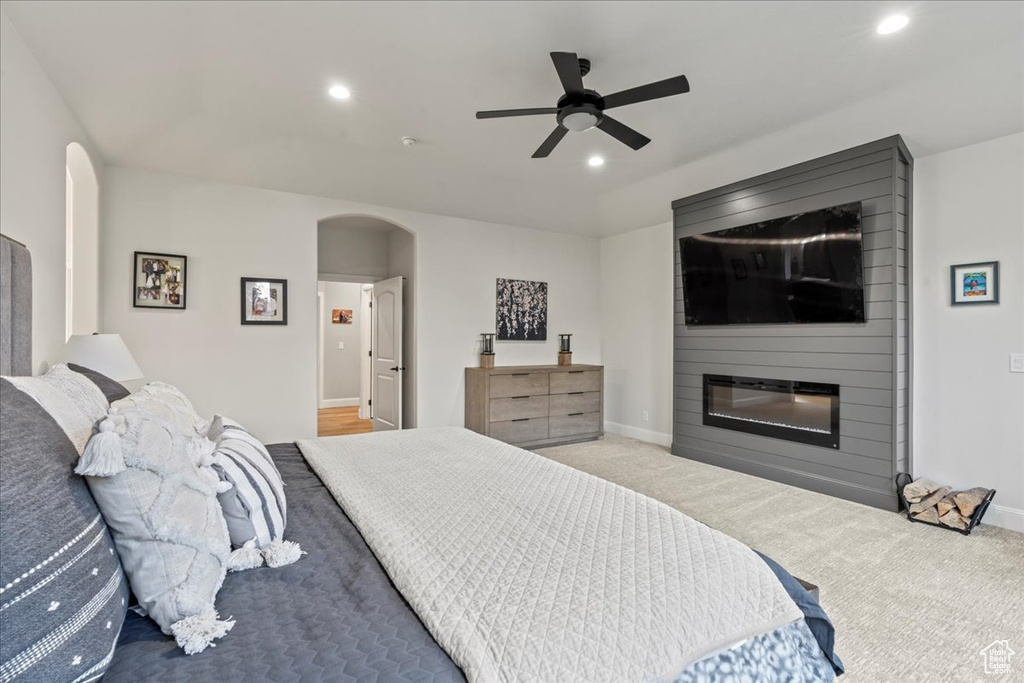 Bedroom with a large fireplace, ceiling fan, and carpet