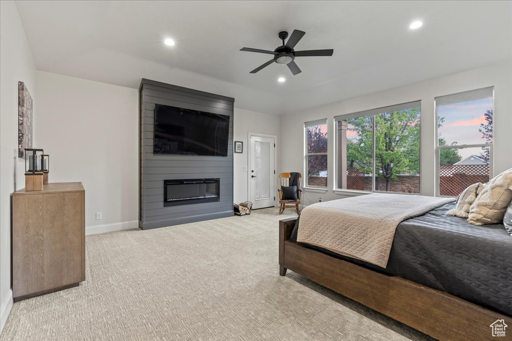 Bedroom with light colored carpet, ceiling fan, and a fireplace
