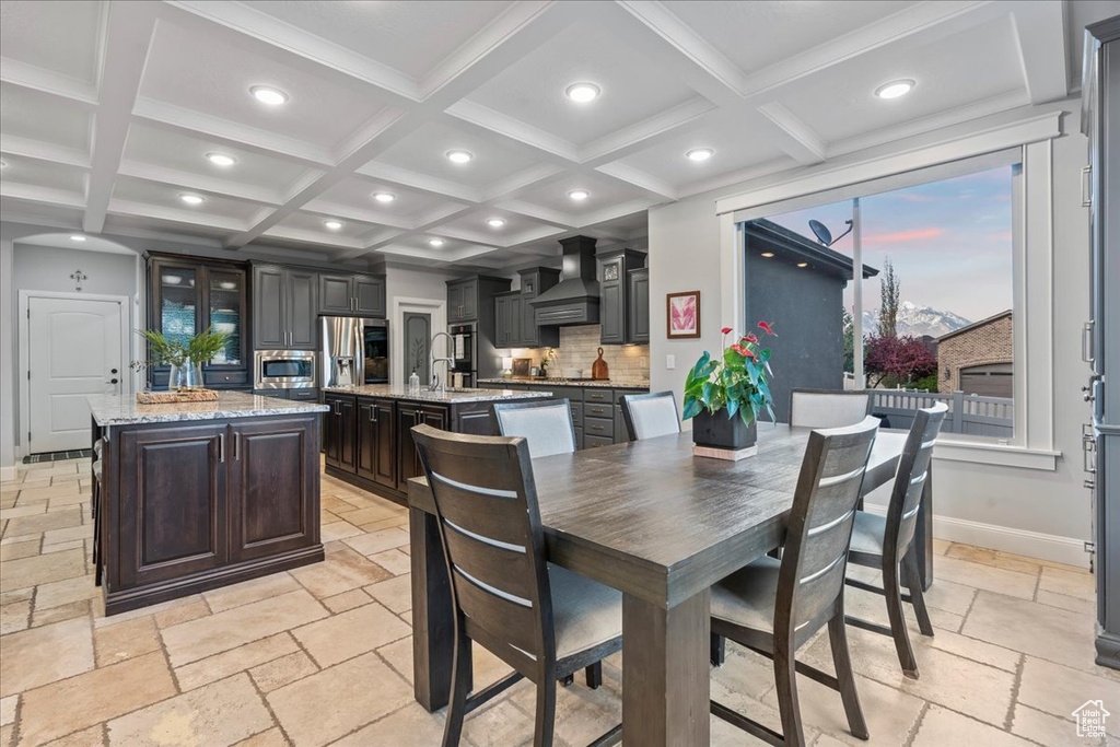 Dining room featuring coffered ceiling, beamed ceiling, and light tile floors