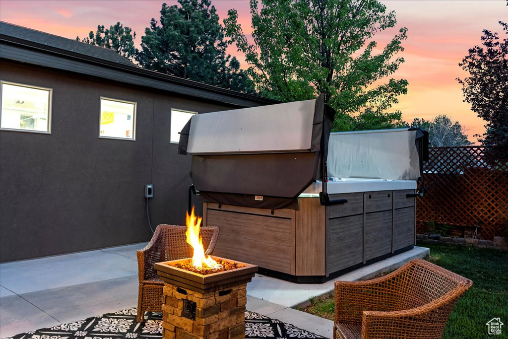 Patio terrace at dusk with a fire pit and a hot tub