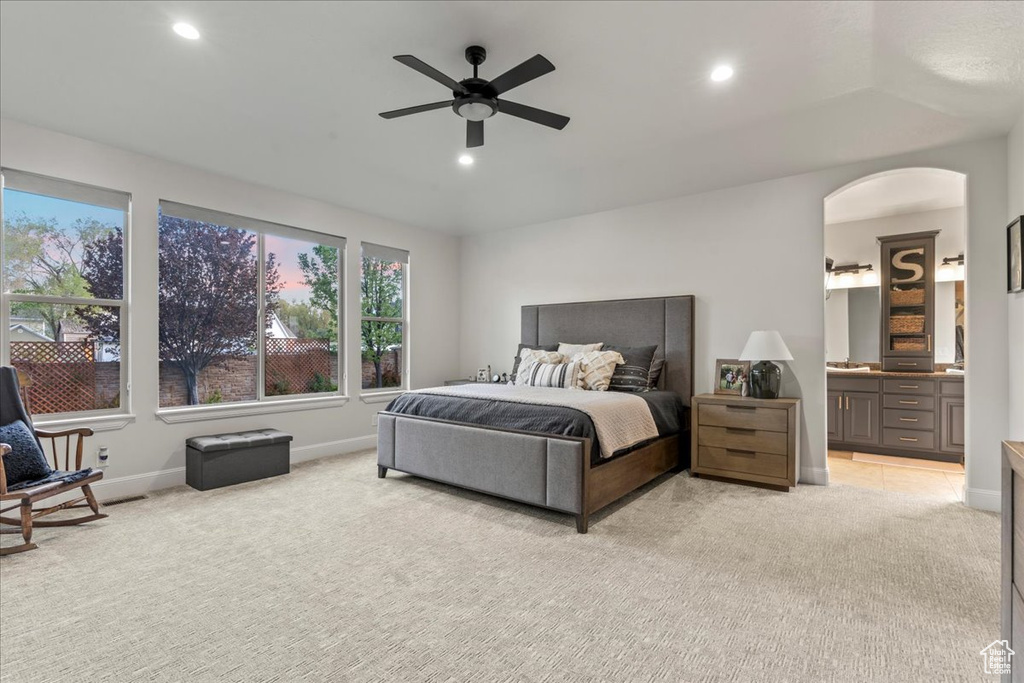 Bedroom featuring light carpet, ceiling fan, and ensuite bath