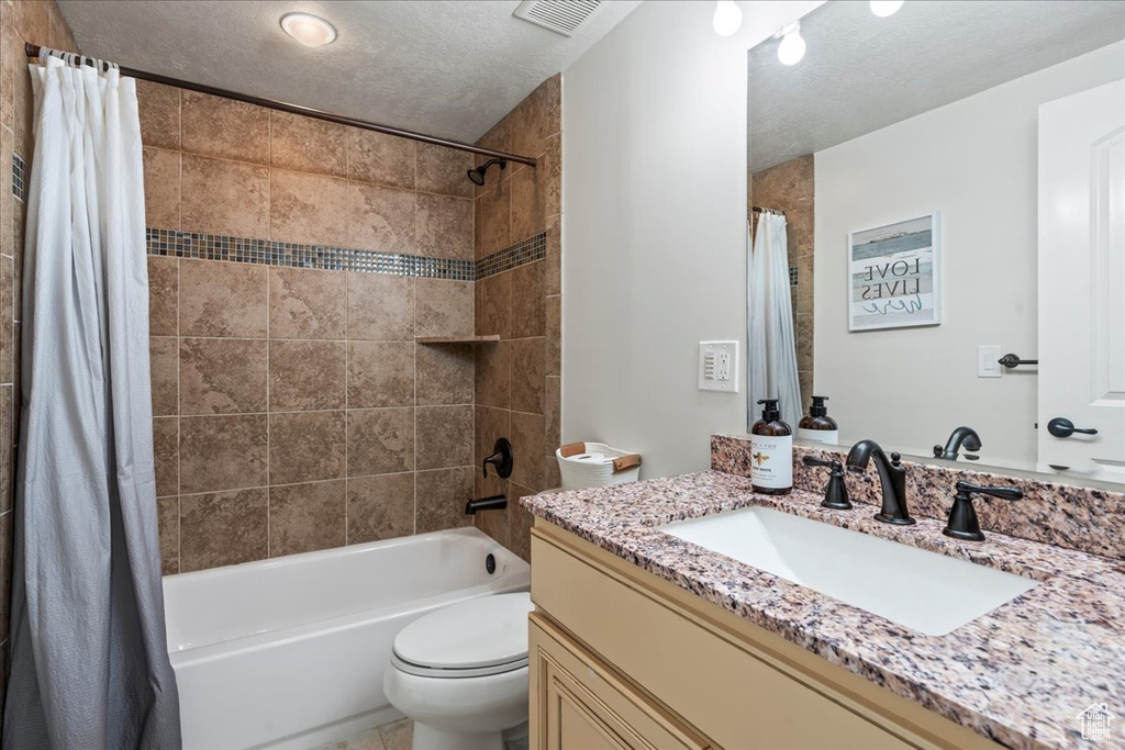 Full bathroom with shower / tub combo, vanity, toilet, and a textured ceiling