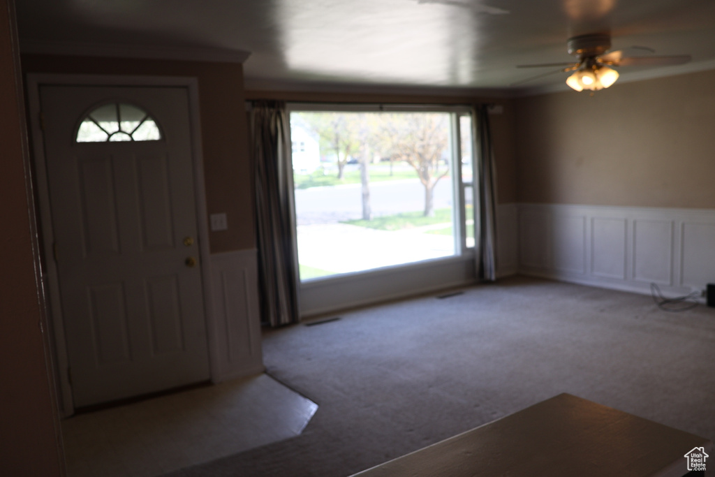 Carpeted entryway with a healthy amount of sunlight and ceiling fan