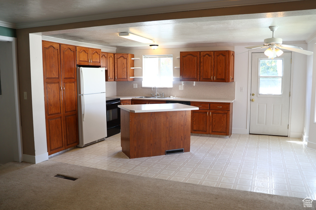 Kitchen featuring white fridge, ceiling fan, a wealth of natural light, and a kitchen island
