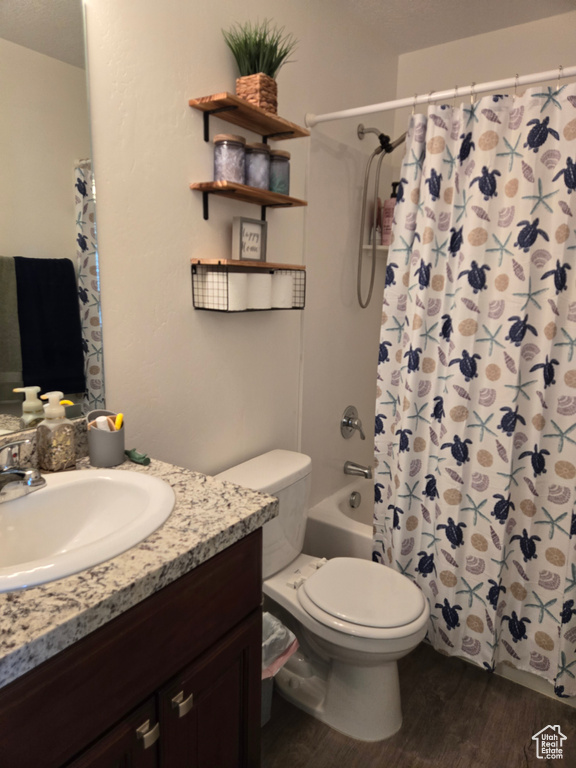 Full bathroom with hardwood / wood-style floors, shower / tub combo, vanity, and toilet