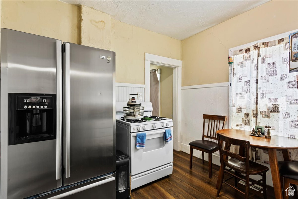 Kitchen featuring stainless steel refrigerator with ice dispenser, white range with gas cooktop, and dark wood-type flooring