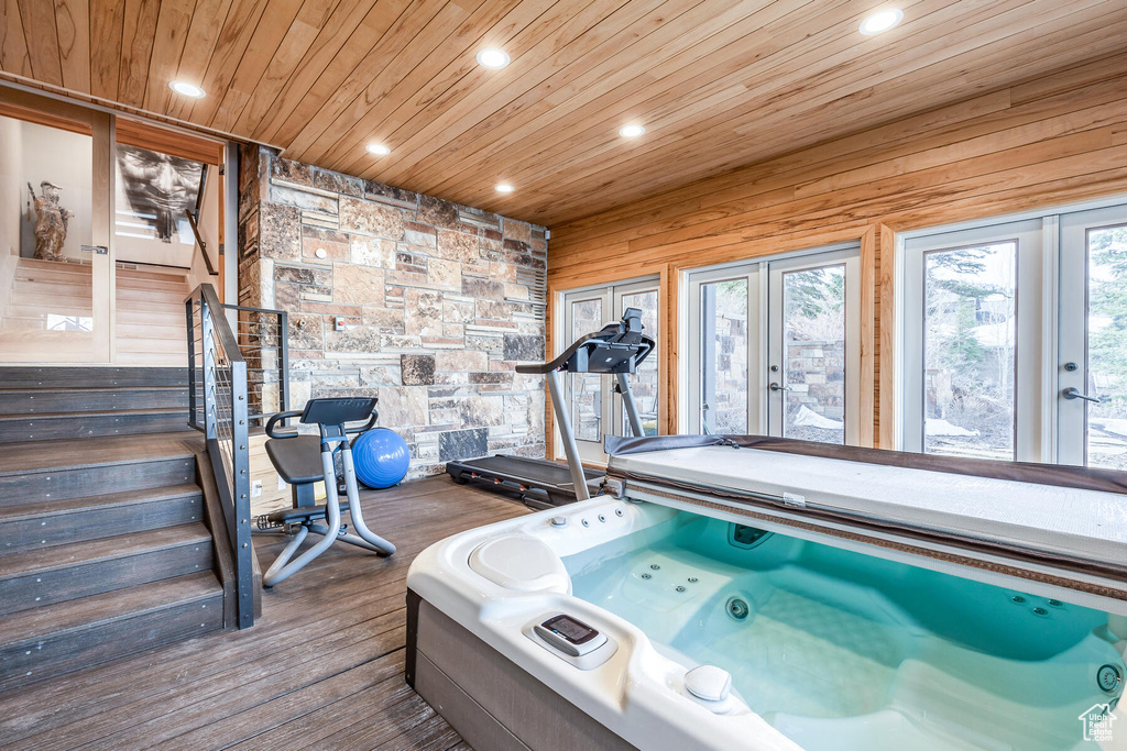 Recreation room with wood walls, french doors, dark hardwood / wood-style flooring, and a hot tub