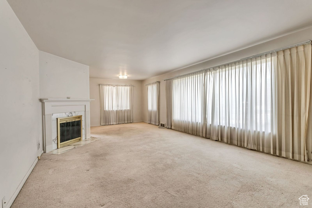 Unfurnished living room with light colored carpet and a high end fireplace