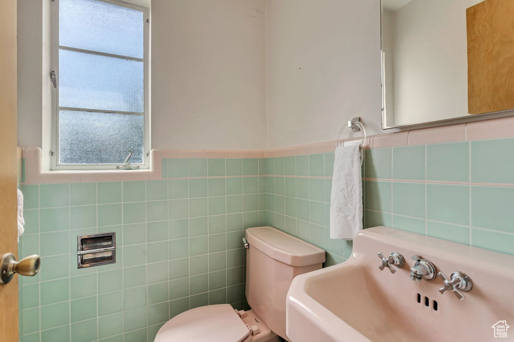 Bathroom featuring tasteful backsplash, toilet, tile walls, and sink